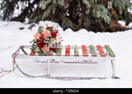 Beau bouquet de mariage se trouve sur un traîneau pour équitation d'hiver sur la neige blanche dans un parc couvert de neige Banque D'Images