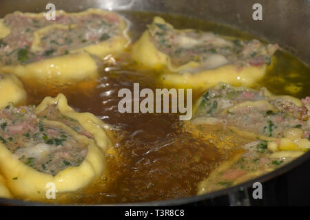 Deliciois maultaschen souabe rempli de viande et d'épinards, des raviolis à la viande souabe laminées en flottant dans un bouillon chaud pot métal Banque D'Images