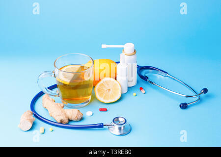 Préparations froides, stéthoscope, thé, citron et gingembre sur un fond bleu. Banque D'Images