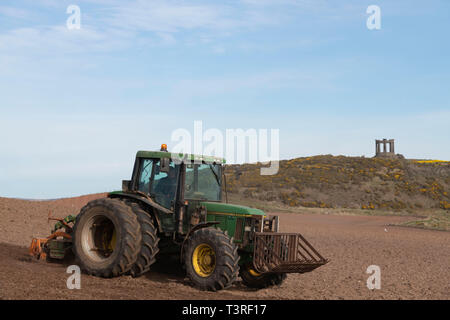 Un agriculteur herse un champ sous le monument aux morts près de Stonehaven dans Aberdeenshire Banque D'Images