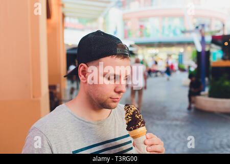 Homme barbu court eating ice cream cone dans une rue de la ville. Banque D'Images