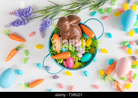 Close-up of Easter basket with chocolate bunny, mini-carottes, des bonbons et des oeufs sur fond blanc Banque D'Images