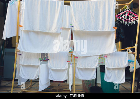 Le séchage des vêtements inhabituels dans le coucher du soleil. Serviettes et draps blancs sécher au soleil sur des cordes tendues blanchisserie. Lessive du linge est séché dans Banque D'Images