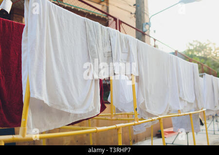 Le séchage des vêtements inhabituels dans le coucher du soleil. Serviettes et draps blancs sécher au soleil sur des cordes tendues blanchisserie. Lessive du linge est séché dans Banque D'Images