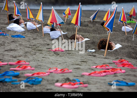 Japon : Ibusuki. L'île de Kyushu, Onsen (source chaude japonaise) sur la plage. Femmes enterrées dans le sable avec juste la tête qui sort, sous un parasol Banque D'Images