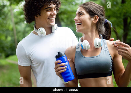 Couple boit de l'eau après la course pour refaire le plein d'énergie et d'hydrater Banque D'Images