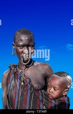 Femme avec bébé en écharpe, tribu Mursi, Mago Parc National, région du sud de l'ONU des nationalités et des peuples, de l'Éthiopie Banque D'Images