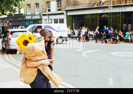 Londres/UK - 22 juillet 2018 : Jeune femme avec bouquet de fleurs achetées sur le Columbia Road Flower Market dans l'Est de Londres, Royaume-Uni Banque D'Images