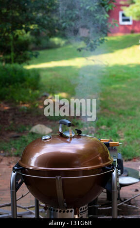 Fumeur barbecue en premier plan avec pelouse, arbres, et grange rouge en arrière-plan. Banque D'Images