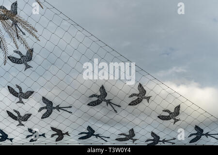 Cairns, Australie - Février 17, 2019 : Net d'oiseaux artwork par Dennis Nona sur le quai. Chiffres noirs contre ciel nuageux gris. Banque D'Images