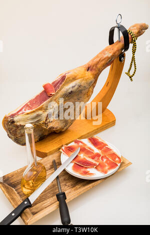 Jambon Serrano espagnol sur la jambe avec porte-bois - isolé Banque D'Images