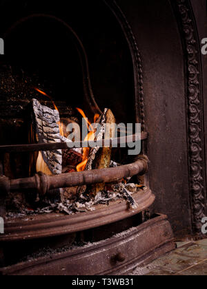 Un feu ouvert avec les journaux en partie brûlé dans une cheminée victorienne. Banque D'Images