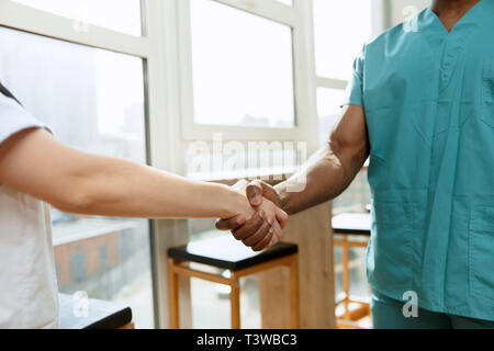 Faire face. Concept de collaboration en médecine. La photo en gros plan de deux médecins se serrer la main sur l'hôpital. arrière-plan gris Droit de publicité au sujet des soins de santé, santé, clinique, de la médecine et de l'équipe. Banque D'Images