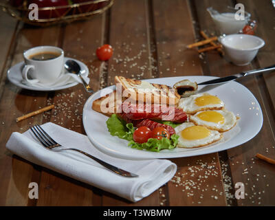 Plusieurs oeufs frits sont servis sur une assiette avec de la saucisse et salade verte avec des tomates rouges frais. Banque D'Images