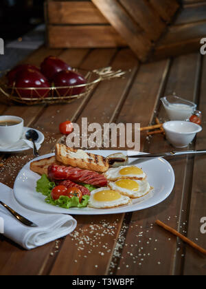 Plusieurs oeufs frits sont servis sur une assiette avec de la saucisse et salade verte avec des tomates rouges frais. Banque D'Images