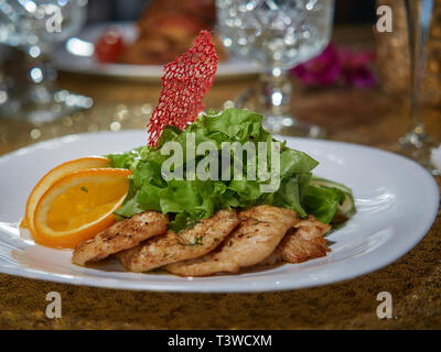 Morceaux de viande fraîche de porc frit sur un feu ouvert. Servi avec des tranches de citron vert et de la laitue. Banque D'Images