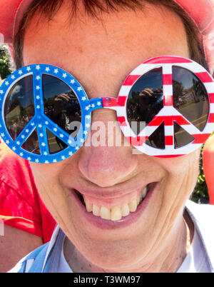 Heureux, smiling woman funny, patriotique signe de paix à lunettes de soleil. Fun Quatrième de juillet costumes des défilés. Banque D'Images