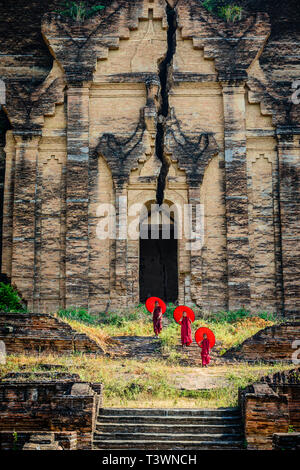 Les moines d'Asie sous les parasols debout près de temple historique, Mingun, Mandala, Myanmar Banque D'Images