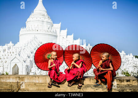 Les moines asiatiques assis sous les parasols près de temple historique, Mingun, Mandala, Myanmar Banque D'Images