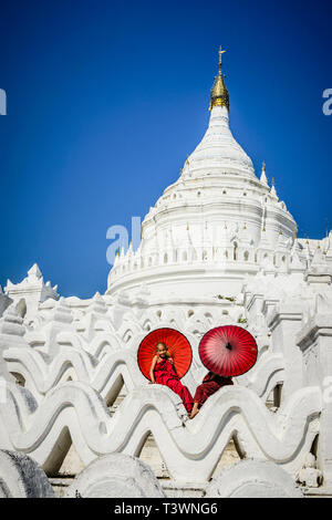 Les moines asiatiques assis sous les parasols au temple historique, Mingun, Mandala, Myanmar Banque D'Images