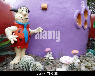 Hillsborough, USA. Apr 11, 2019. Une figure de Fred Feuerstein (Fred Flintstone), devant une maison à peintes de couleurs vives dans un style inhabituel Hillsborough près de San Francisco. Une californienne décoré sa maison avec inhabituelle Flintstone dinosaures d'un mètre de haut et d'autres chiffres. Pour certains fonctionnaires de la ville à cet endroit qui en jette, c'est une tache. Maintenant la construction litige est d'aller en cour. Crédit : Barbara Munker/dpa/Alamy Live News Banque D'Images