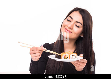 Black-haired girl eating sushi avec des baguettes un, isolé Banque D'Images