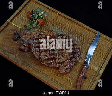 Boeuf Angus américain bifteck de faux-filet grillé sur une planche de bois à l'aide d'un couteau Banque D'Images