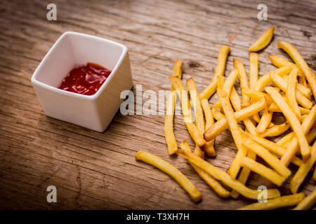De délicieuses frites et du ketchup sur la vieille table en bois Banque D'Images