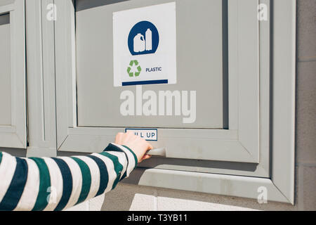Une personne ouvre ou ferme un bac moderne des déchets pour la collecte séparée des déchets. Banque D'Images