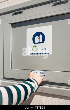 Une personne ouvre ou ferme un bac moderne des déchets pour la collecte séparée des déchets. Banque D'Images