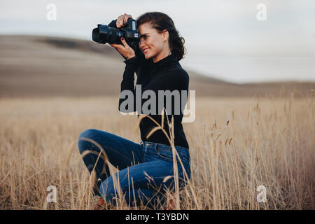 Jeune femme à l'aide de votre appareil photo reflex numérique pour prendre des photos à l'extérieur. Femme photographe professionnel pour prendre des photos avec un reflex numérique. Banque D'Images