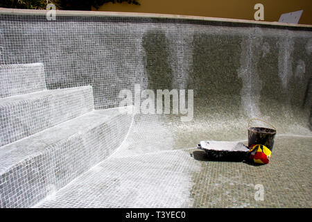 Le jointoiement du carrelage mosaïque en cours sur une fuite dans une piscine. Banque D'Images