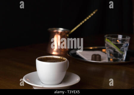 Un verre de café avec café et chocolat à côté d'un café au lait dans une tasse blanche placée sur une table marron Banque D'Images