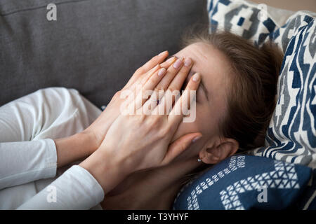 Close up contrarié frustrated woman couvrant le visage avec les mains, lying on sofa Banque D'Images