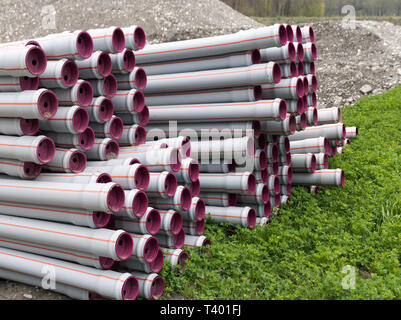 De nombreux tubes en plastique long empilées prête pour la construction d'un système d'approvisionnement en eau et d'irrigation agricole sur le motif Banque D'Images