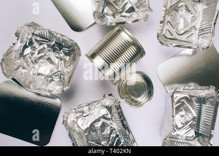 Concept de la pollution plastique. Papier aluminium contenant de l'argent pour la nourriture, d'argent et de cartons de boîtes en métal sur fond blanc, vue du dessus. En plastique à usage unique Banque D'Images