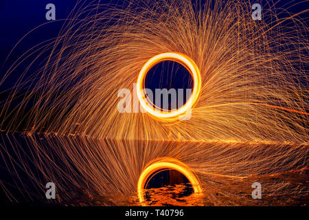 Peinture de lumière. Affichage pyrotechnique de nuit avec le reflet de l'eau Banque D'Images