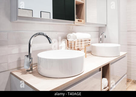 Deux robinet de luxe sur un mélangeur de lavabo blanc bol rond dans une belle salle de bains gris beige Banque D'Images