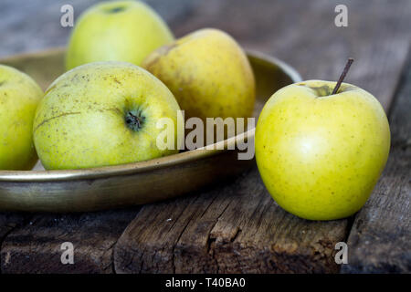 Pommes jaune-vert frais se situent dans une ancienne plaque en laiton sur une vieille table rustique, de texture, Soft focus, place pour le texte. Banque D'Images