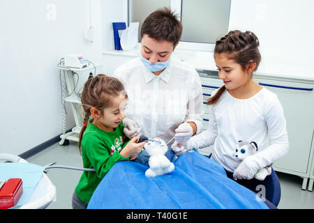 Le médecin indique les petites filles la procédure pour le traitement des dents. Femme dentiste enregistrer atmosphère de calme et de pureté en particulier pour les jeunes pati Banque D'Images