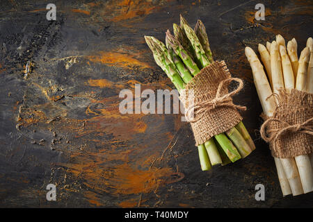 Frais vert et blanc de printemps les asperges lié en bottes avec de la ficelle et mouche sur un fond de métal rouillé with copy space Banque D'Images