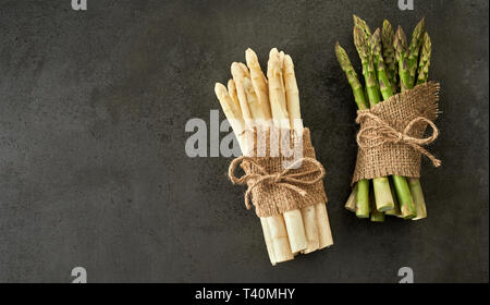 Frais vert et blanc de printemps de l'Asparagus attachés en deux bundles avec chaîne et de Hesse sur un fond texturé gris with copy space Banque D'Images