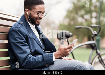 Toujours en contact. African businessman using smartphone outdoors Banque D'Images