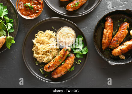 Close up de saucisses grillées avec de la choucroute et au raifort sur plaque sur fond noir en noir. Haut de la vue, télévision lay Banque D'Images