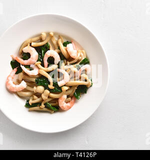 Close up of sauté de champignons en hêtre blanc avec des feuilles d'épinard et crevettes sur fond noir en blanc. Haut de la vue, télévision lay Banque D'Images