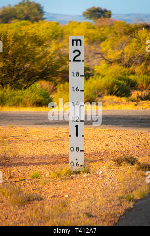 Façon d'inondation de la rue à côté de l'indicateur de profondeur Australian Outback road Banque D'Images