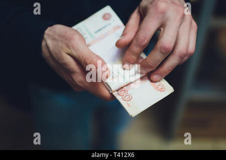 L'homme de donner de l'argent, billets, Rouble russe sur son bureau dans un bureau sombre - corruption concept.billets en roubles russes. Thème financier Banque D'Images