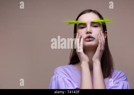 Femme d'épillets vert sur les sourcils touching her face Banque D'Images