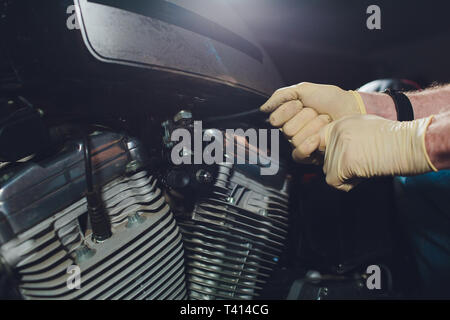 Man fixing bike. Jeune homme confiant la réparation de près de son garage moto. Banque D'Images