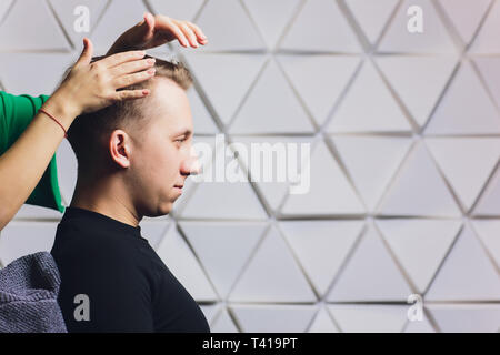 Coiffure femme homme son séchage des cheveux du client dans son salon de coiffure. Banque D'Images